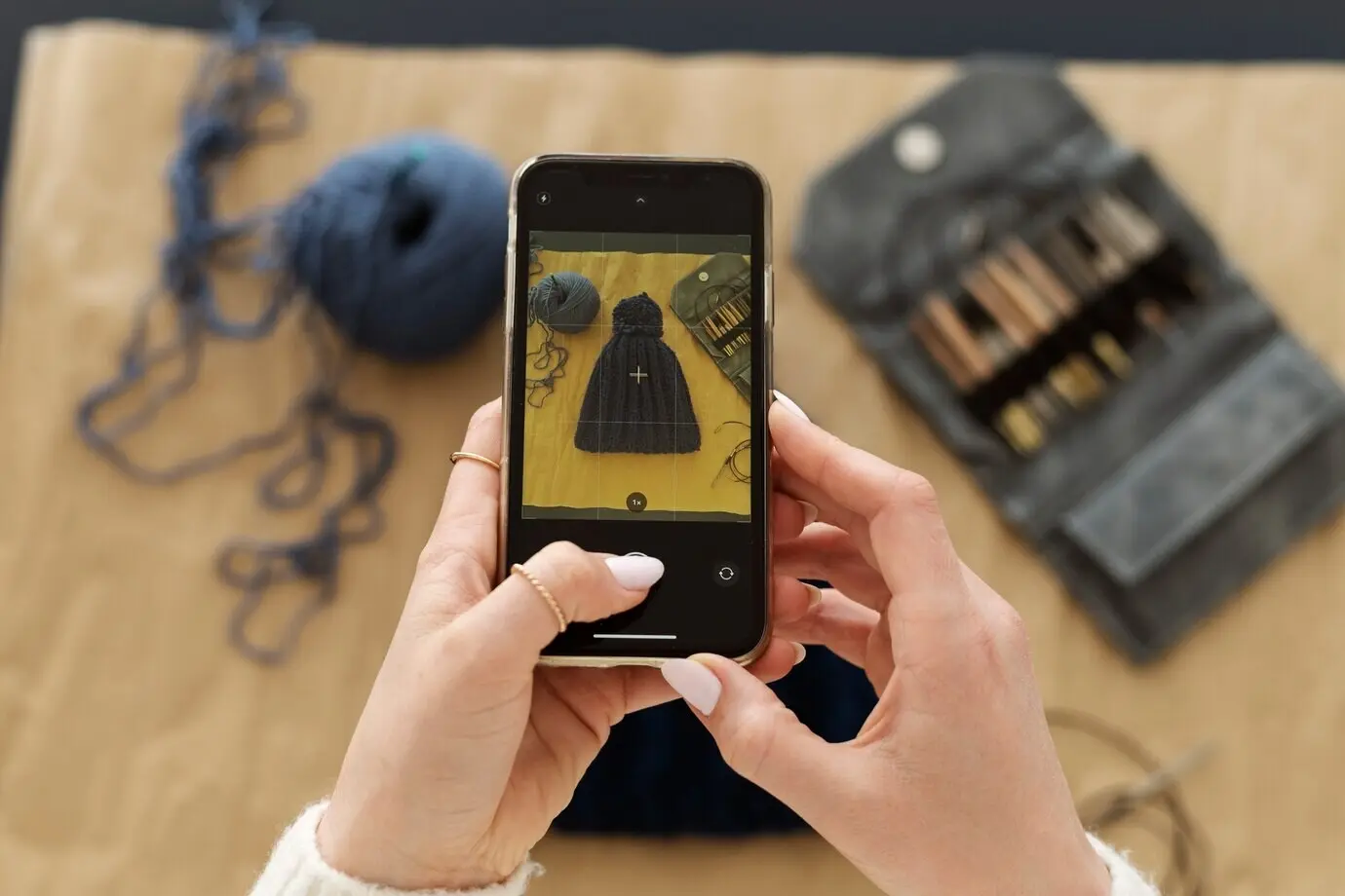 Молодой взрослый человек фотографирует своё вязаное изделие.